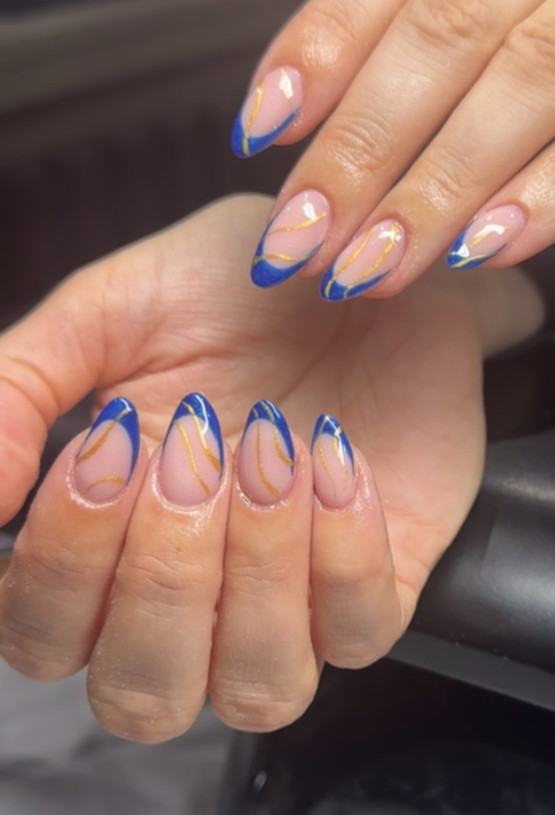 Blue and gold swirled nail art on a soft pink base